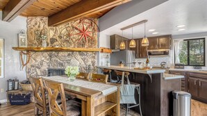 Una cocina moderna con una pared de acento de piedra, mesa de comedor de madera e iluminación colgante.