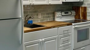 Een moderne keuken met witte kasten, een inbouwmagnetron, een fornuis en een koelkast.