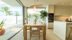 A modern kitchen with a dining area, large windows, and potted plants. - Sunny Villa by Platja Ardiaca (Cambrils)