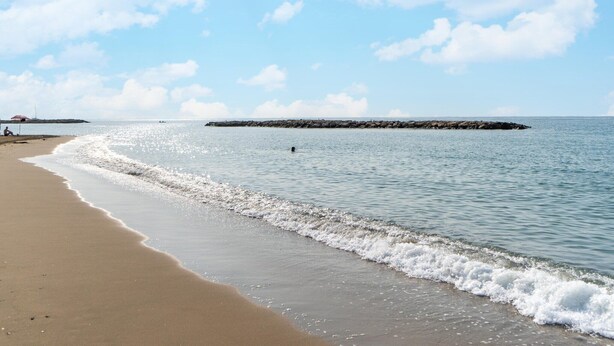 A beach with calm waves, a distant rocky outcrop, and a clear sky. - Sunny Villa by Platja Ardiaca (Cambrils)