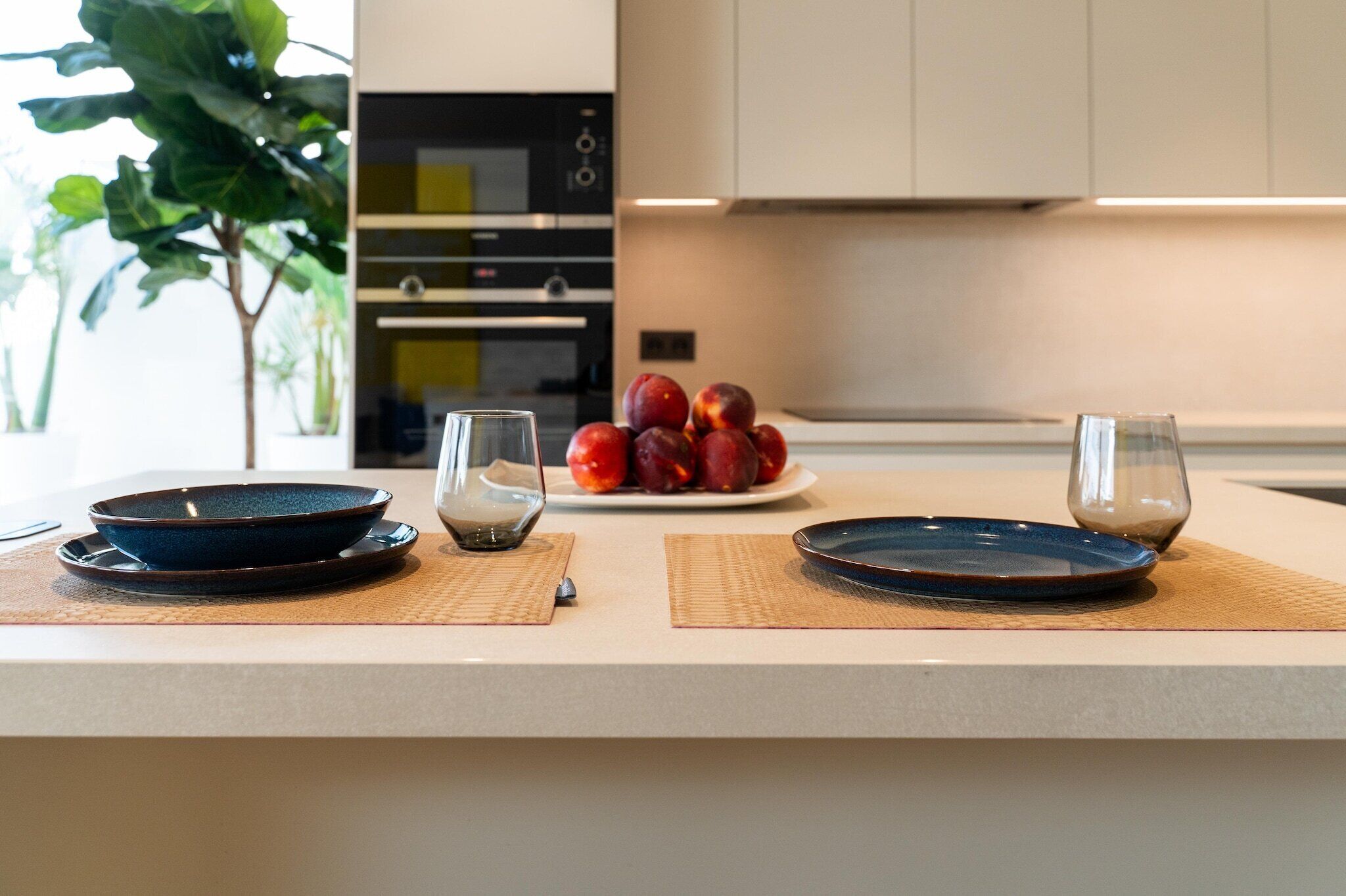 A modern kitchen with a central island, a fruit bowl, and two glasses.