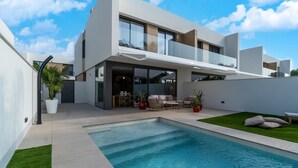 A modern two-story house with a swimming pool, outdoor seating area, and a large glass door leading to the interior. - Sunny Villa by Platja Ardiaca (Cambrils)