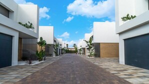 A modern building with a central courtyard, featuring a paved walkway and potted plants. - Sunny Villa by Platja Ardiaca (Cambrils)