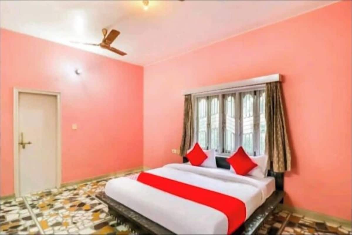 A bedroom with a bed, a ceiling fan, a window with curtains, and a door.