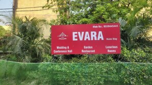 Een rood bord met de tekst EVARA, waarop diensten staan vermeld zoals een trouw- en congrescentrum, een restaurant in de tuin en luxe kamers.