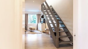 Un interior moderno con una escalera de madera que sube a un nivel superior.