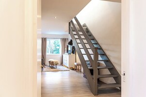 Un interior moderno con una escalera de madera que sube a un nivel superior.