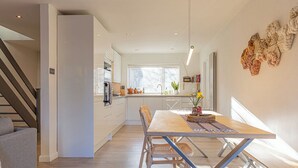 Una cocina moderna con comedor, piso de madera y una escalera.