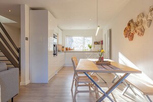 Una cocina moderna con comedor, piso de madera y una escalera.