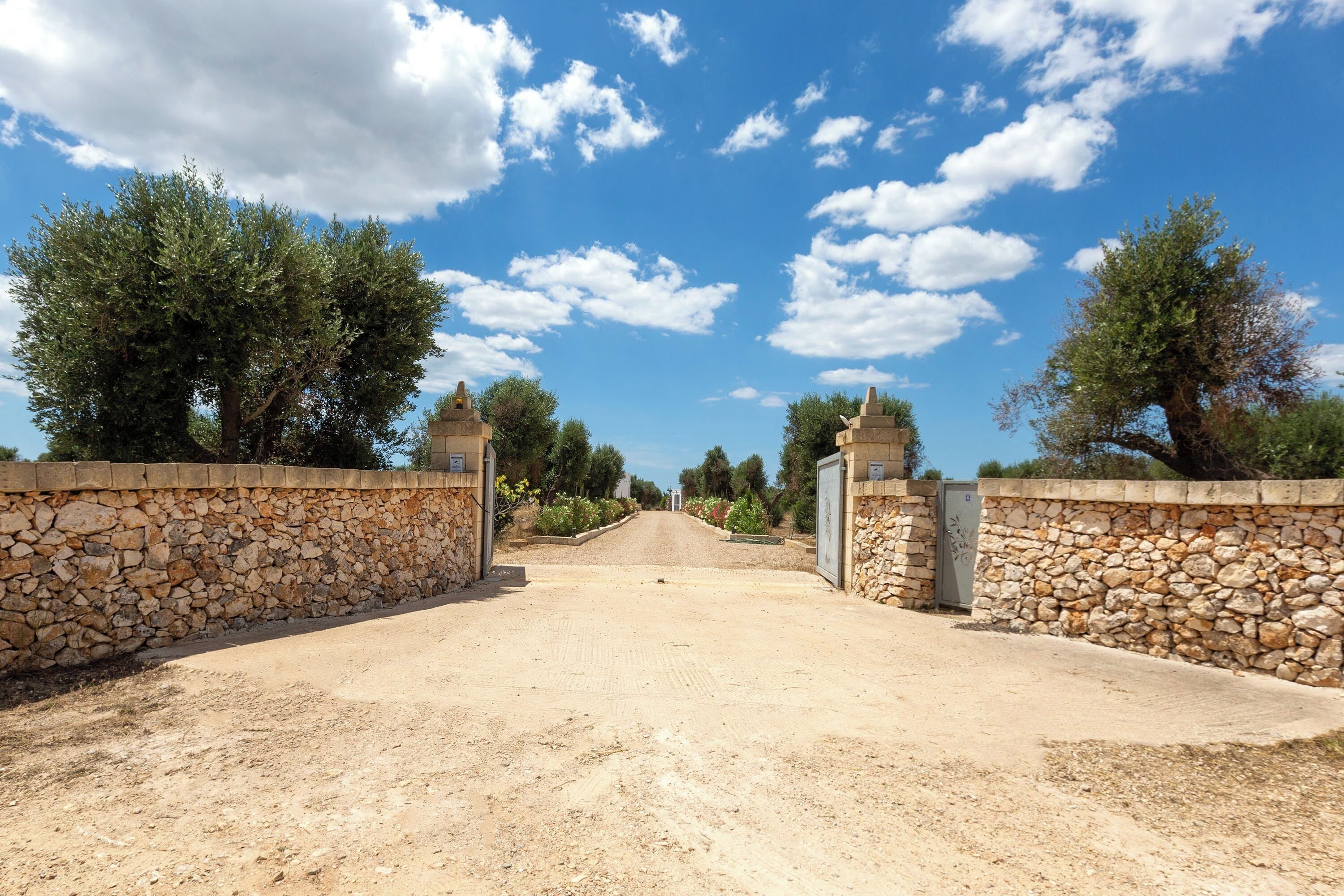 Un camino pavimentado que lleva a una puerta de piedra, con cielo despejado.