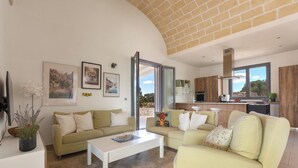 A modern living room with a sofa, coffee table, and a view of the kitchen. - 4134 Villa Majer by Perle di Puglia (Manduria)
