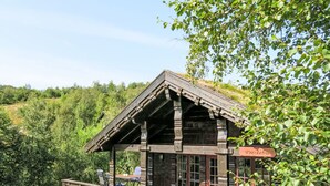 Una baita di legno con un portico coperto, un cartello con la scritta 'Presteber' e vista su un pendio boscoso.