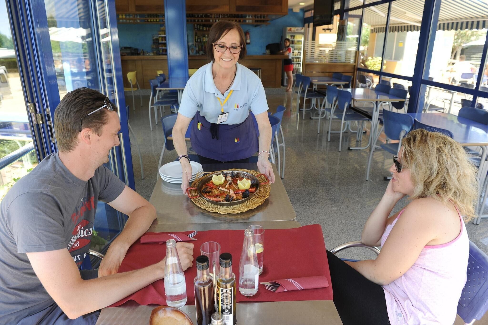 Un restaurante con un camarero sirviendo un plato de mariscos a una mesa.