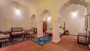 Une pièce comprenant un canapé, des fauteuils, un lit et un tapis bleu à motifs.