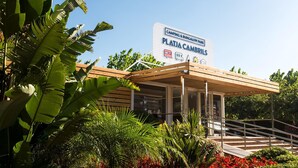 A sign for Platja Cambriol's camping and bungalow park with a covered entrance and stairs.