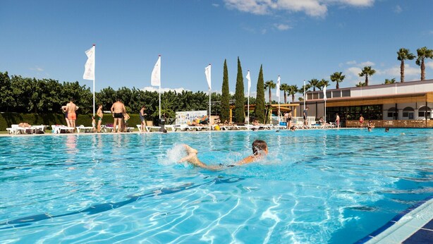 A swimming pool with people in the water and on the poolside.
