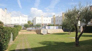 A courtyard with a stone pathway leading to a seating area, surrounded by buildings with uniform architecture.