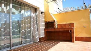 A modern outdoor area with a tiled floor, a brick fireplace, and a sliding glass door.