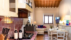 A kitchen with a tiled backsplash, a stove, and a dining area with a table and chairs. - Il Castellare, a delightful apartment in the heart of Sierna (Siena)