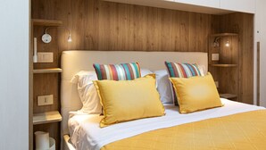 A modern bedroom with a wooden headboard, two bedside tables, and a bed with yellow bedding and striped pillows. - Il Castellare, a delightful apartment in the heart of Sierna (Siena)