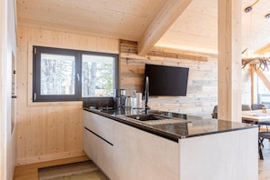 Una cocina moderna con paredes de madera, un ventanal grande y un televisor de pantalla plana.