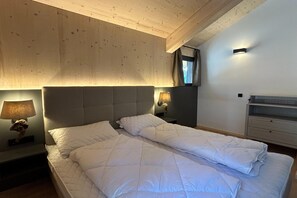 Un dormitori amb un llit gran, dues làmpades de nit, una tauleta de nit i un aparador.