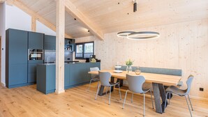 A modern kitchen with blue cabinets, a wooden dining table with four chairs, and a pendant light.