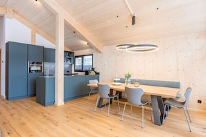 Una cocina moderna con armarios azules, una mesa de comedor de madera con cuatro sillas y una lámpara colgante.