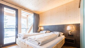 Un letto di legno con testiera, due lampade sui comodini e vista sull'esterno tramite una porta vetrata.