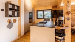 Una cucina moderna con elementi in legno, forno integrato e angolo caffè.