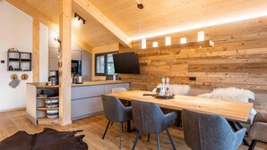 Una cucina moderna con soffitto in legno, una zona pranzo con sedie grigie e un grande tavolo di legno.