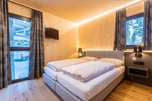 Um quarto aconchegante com cama, televisão e janela com cortinas.