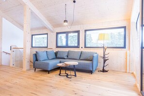 A wooden interior with a sofa, a small table, and a lamp.