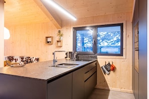 Una cocina moderna con paredes de madera, un ventanal grande y electrodomésticos integrados.