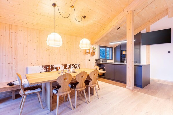 A wooden interior with a dining area, kitchen, and a TV mounted on the wall.