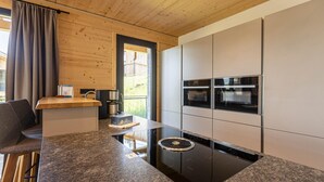 A modern kitchen with granite countertops, built-in ovens, and a central island with a sink and coffee maker. - Superior chalet withsauna & hottub (Turrach)