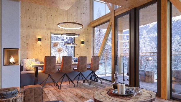 A cozy cabin interior with a wooden interior, a dining area with chairs, a fireplace, and a large window offering a snowy mountain view. - Superior chalet withsauna & hottub (Turrach)