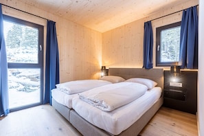A room with two beds, wooden walls, and large windows with curtains. - Welcoming chalet with sauna & hot tub (Turrach)