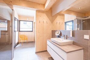 Un baño moderno con un espejo grande, un lavamanos y una ducha.