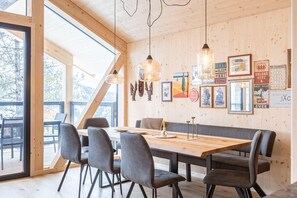 A wooden interior with a long dining table, chairs, and a bench.