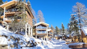 A snow-covered mountain lodge with multiple balconies and a clear blue sky. - Lavish chalet with sauna (Turrach)