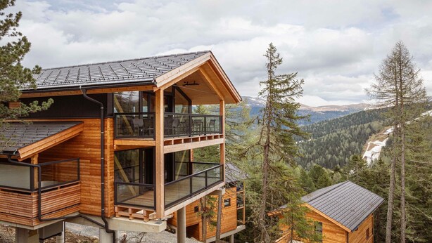 A modern wooden cabin with a glass balcony, set in a mountainous area with a view of the valley. - Lavish chalet with sauna (Turrach)