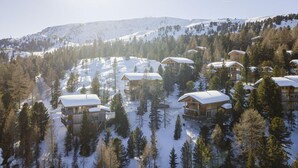 Ein schneebedecktes Bergresort mit mehreren Holzhütten und einer Skipiste.