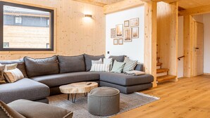 Ein modernes Wohnzimmer mit Ecksofa, rundem Couchtisch und einer Treppe, die in eine andere Ebene führt.