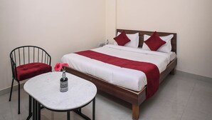 A neatly arranged bedroom with a bed, a small round table, and a chair. - Raj Residency (Jodhpur)