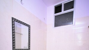 A bathroom with a pedestal sink, a toilet, and a mirror with a decorative frame. - Raj Residency (Jodhpur)