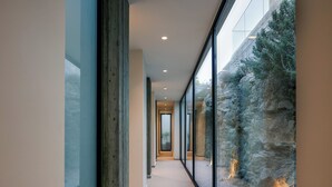 Ein moderner Flur mit Glaswänden, einer Steinwand und Blick auf eine felsige Landschaft.