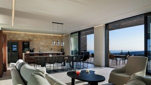 Ein moderner Wohnbereich mit einer Wand aus Stein, einem Esstisch und einem großen Fenster mit Blick auf die Landschaft.