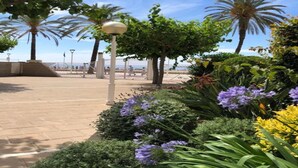 A paved walkway with palm trees and flowering plants. - Bungalow in Sant Salvador near Beaches (Tarragona)