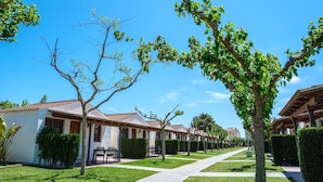 A row of single-story buildings with a consistent architectural style, a paved walkway, and well-maintained landscaping. - Bungalow in Sant Salvador near Beaches (Tarragona)